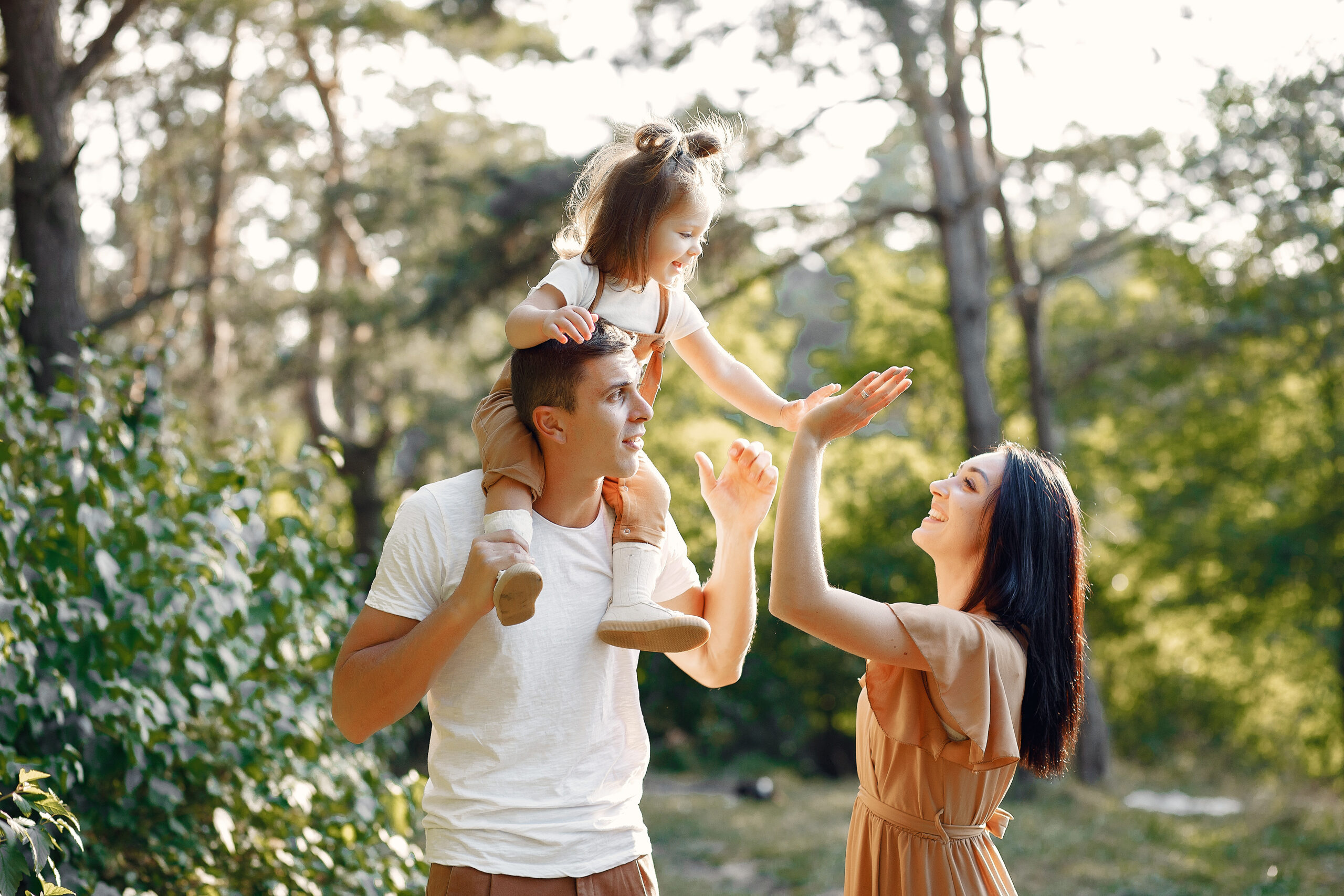 Family with cute little daughter. Father in a white t-shirt. Lady in a brown dress.